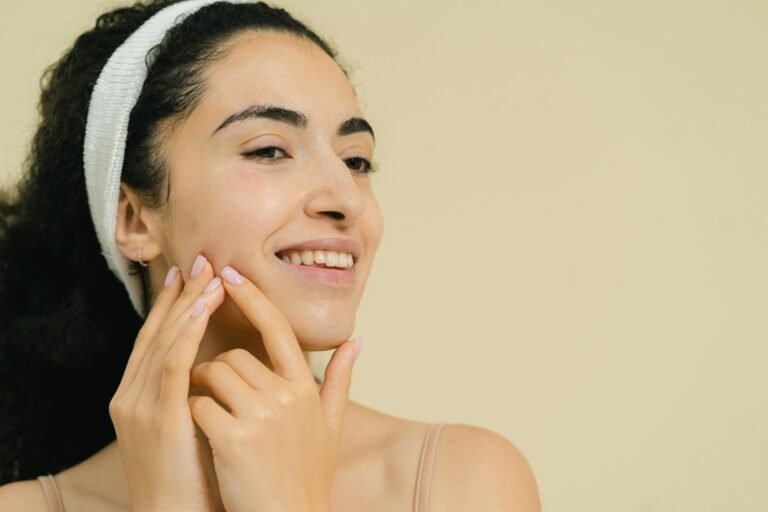 Close-up of a smiling woman applying skin treatment, promoting natural beauty and skincare.